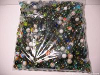 Full view of sealed plastic bag containing 716 assorted glass marbles with various colors, including amber, white, blue, green, and multicolored swirls and stripes.