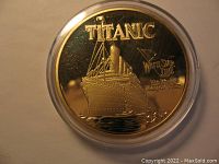 Front side of the gold plated Titanic commemorative coin showing ship and White Star Line flag