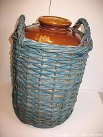 Full view of antique stoneware milk barrel encased in blue painted wicker with handles