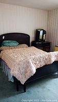 Photo of the bed made with floral pattern bed linens on wood frame headboard and mattress shown
