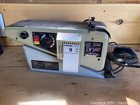Left side view of the Shopcraft 4 inch belt sander showing the control panel with speed dial and power switch, device powered by electricity.