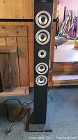 Tall black tower speaker with five round drivers visible frontally.