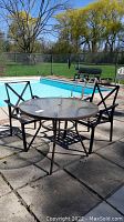 Patio table and chairs arranged on outdoor patio by pool.