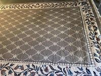 Full view of the rectangular rug showing the grey diamond lattice patterned center and the floral border
