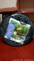 Black circular carrying bag for the Outdoor Escapes 6-foot pop-up screen room with product label visible.