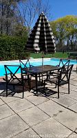 Full view of patio dining set by pool including table, four chairs, and umbrella