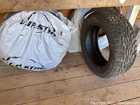 Four Uniroyal Tiger Paw Ice and Snow M/S tires, one unwrapped showing tread pattern and three wrapped in plastic.