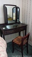 Full view of wooden vanity table with tri-fold mirror and two drawers, visible scratches and wear on surface.