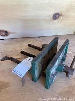Cast iron woodworking vice showing full body and screw mechanism on wooden surface.