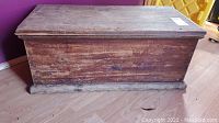 Front view of vintage wooden chest showing worn finish and missing hinges