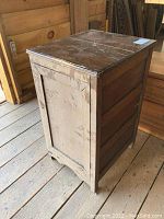 Side view of vintage wooden cupboard showing damaged side panel and worn paint.