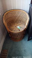 Full view of the barrel-shaped wicker chair with natural light brown woven material and black accents