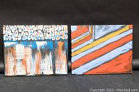 Both abstract oil paintings by Andrew Mackie side by side on a black backdrop