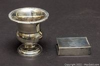 Front angle showing Birks sterling silver bud vase with dent and sterling silver matchbox holder on a dark surface.