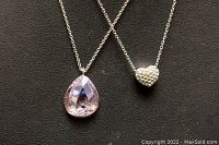 Two Swarovski necklaces on black surface showing teardrop crystal and heart pendants