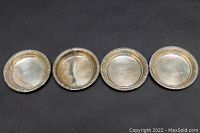 Four round Birks sterling silver coasters laid flat on dark background showing tops
