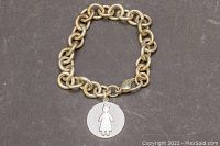 Photo of 7 inch silver chainlink charm bracelet with round pendant featuring cutout female figure design front side visible