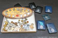 Photo showing 1999 Millennium Canada quarters set arranged on an oval display board, assorted loose coins beneath, and several empty coin cases to the right.
