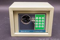 Front view of a beige electronic digital safe with keypad and manual locking handle.