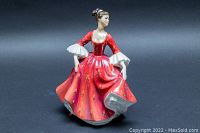 Front-left angle view showing the figurine's red dress with painted floral details and white sleeves.