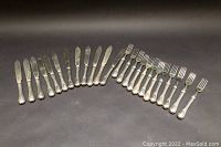 Overall layout of 12 fish knives and 12 forks arranged on black background