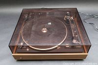Front angle of Dual 510 turntable with closed dust cover showing wood finish sides and power cord.
