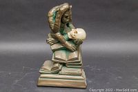 Front view of the vintage signed sculpture showing primate holding a skull, sitting on books.