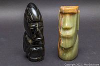 Front view of black obsidian and marble stone carvings showing tribal faces and polished surfaces