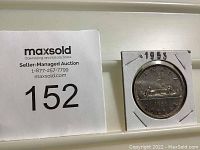 Photo of the 1953 Canadian silver dollar coin in a protective holder with the year marked above.