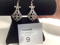 Front view of the pair of vintage silver earrings displayed on black stand