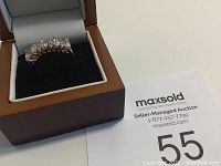 Estate ring shown in a brown leather ring box with padded beige interior and black velvet base insert. Ring features clear marquise and round cut stones set in metal band.