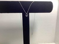 Necklace displayed on black jewelry stand showing teardrop pendant with stone.