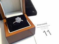 Ring with large clear stone in a wooden box with black velvet insert.
