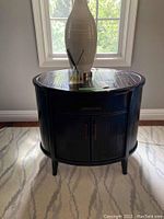 Front view of the brownstone bamboo look side table under window with vase and diffuser on top