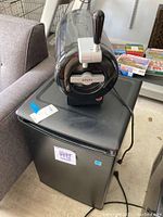 Photo shows Danby mini fridge with Krups mini keg placed on top, cables visible, all items seen on concrete garage floor next to couch and other household items.