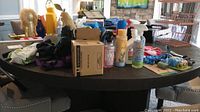 Photo of a table with multiple pet grooming sprays, shampoos, and other dog grooming supply bottles, some in spray cans.