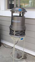 Dynatrap XL bug zapper on top of the cream metal plant stand on a patio