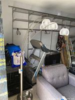 Full view of modern arc floor lamp standing next to furniture and exercise equipment in garage