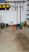 Overview photo showing entire lot with feeders, planters, scarecrow, gardening bags and brooms on garage floor