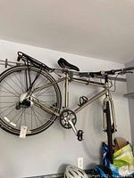 Side view of entire bicycle mounted on wall rack showing frame, wheels, saddle, rear rack
