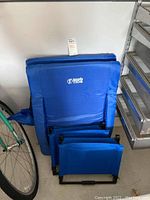 Four blue Brawn Tide foldable stadium seats stacked together showing padding and logo