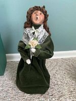 Front view of Byers Choice Caroler figurine with curly brown hair, green dress, white lace shawl, and holding flowers