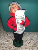 Front view of Byers Choice Caroler figurine showing red coat, gray bonnet with holly, and sheet music scroll