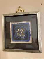 Full view of framed Chinese embossed paper art with friendship symbol and decorative gold hanging element on top