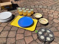 Full lot overview including citronella candles arranged on yellow tray, blue plates stacked, white plates stacked, and other pottery bowls