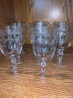 Front view of several etched crystal wine glasses showing the leaf pattern and faceted stems.