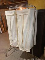 Full view of aluminum clothing rack with two hanging cotton fabric storage units attached, each with flap tops and zippers.