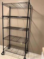 Front view of the entire shelving unit showing all shelves, hooks and caster wheels