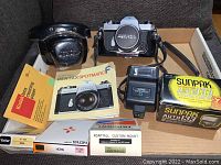 Photo showing entire camera package contents including camera, case, flash unit, filters, manuals, and boxes.