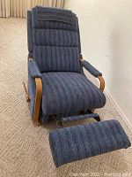 Blue La-Z-Boy rocker recliner reclined with footrest extended on beige carpet.